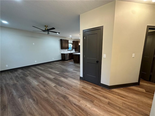 unfurnished living room with a textured ceiling, dark wood-type flooring, and ceiling fan