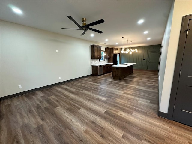 unfurnished living room featuring ceiling fan with notable chandelier and dark hardwood / wood-style flooring