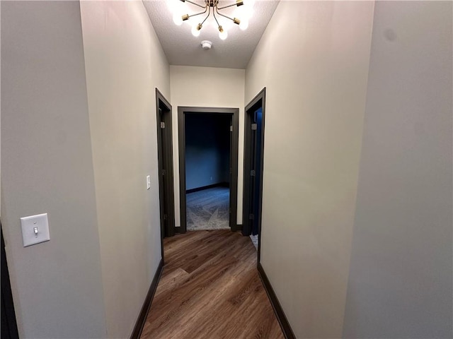 corridor with hardwood / wood-style floors and a chandelier