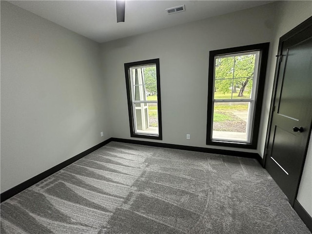 carpeted spare room with ceiling fan and plenty of natural light