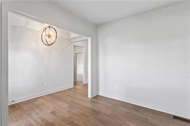 empty room with wood-type flooring and an inviting chandelier