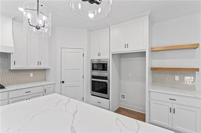 kitchen with appliances with stainless steel finishes, light stone counters, and white cabinets