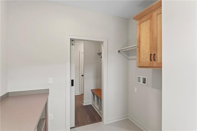 washroom with hookup for a washing machine, wood-type flooring, and cabinets