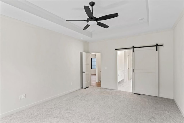 unfurnished bedroom featuring a barn door, a raised ceiling, light carpet, and ceiling fan