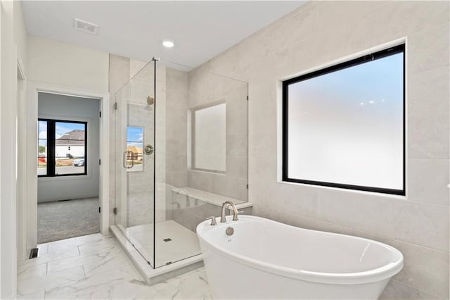 bathroom featuring tile walls and separate shower and tub