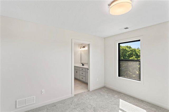 unfurnished bedroom featuring light colored carpet and connected bathroom