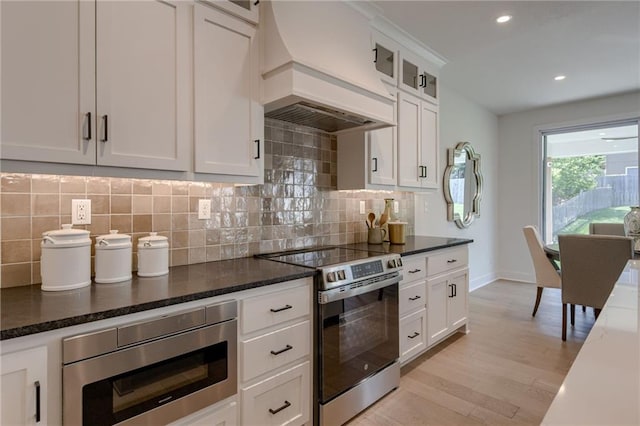 4805 NE 62nd St, Kansas City, MO 64119 - kitchen featuring stainless steel appliances, premium range hood, tasteful backsplash, light wood-style floors, and white cabinetry