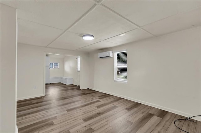 empty room featuring an AC wall unit, hardwood / wood-style floors, and a paneled ceiling