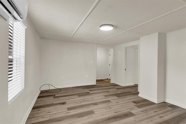 empty room with a healthy amount of sunlight, light wood-type flooring, and a wall unit AC