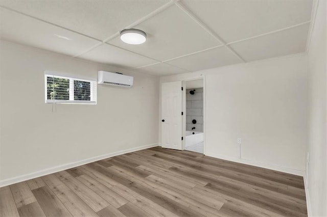 spare room featuring a paneled ceiling, hardwood / wood-style flooring, and an AC wall unit