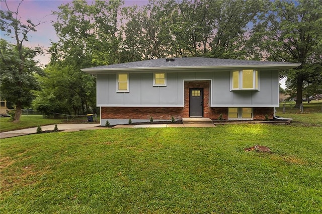 raised ranch with brick siding, board and batten siding, and a front yard