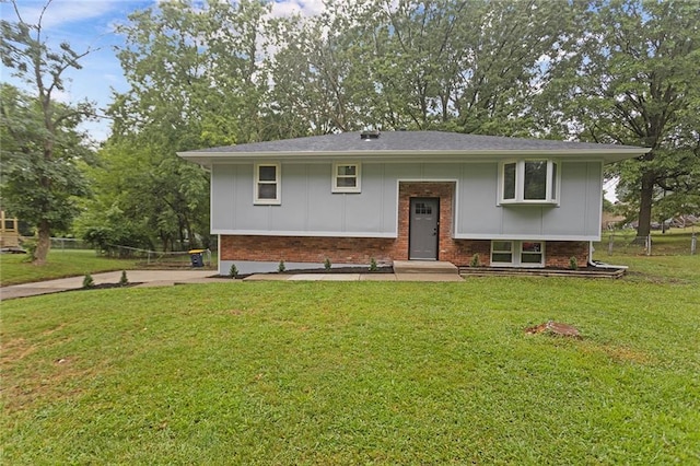 bi-level home featuring brick siding, board and batten siding, and a front yard