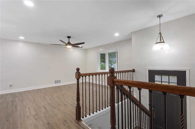 hall featuring an upstairs landing, visible vents, light wood-type flooring, and baseboards