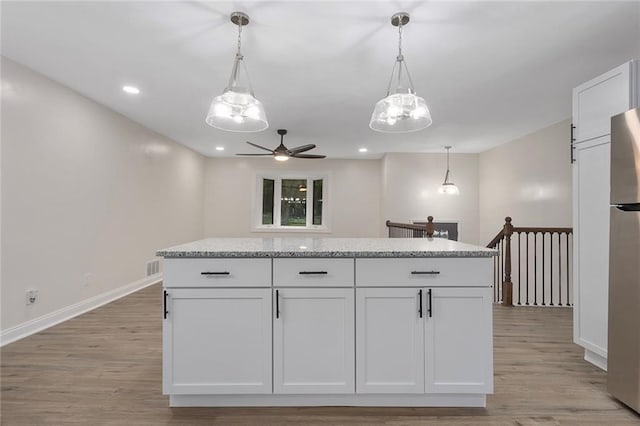 kitchen with light wood finished floors, pendant lighting, white cabinetry, and baseboards