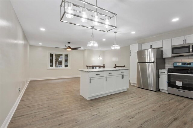 kitchen with stainless steel appliances, decorative backsplash, ceiling fan, white cabinetry, and light hardwood / wood-style flooring