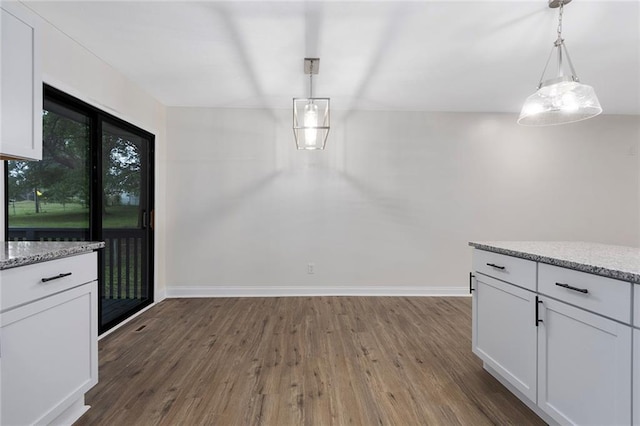 unfurnished dining area with wood finished floors and baseboards