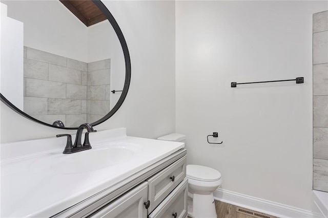 bathroom with visible vents, baseboards, toilet, wood finished floors, and vanity