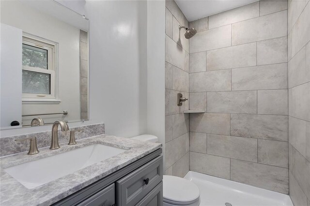 bathroom featuring tiled shower, vanity, and toilet