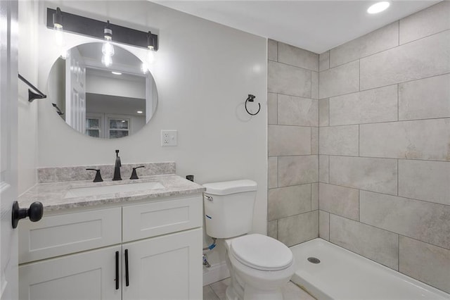 full bathroom with vanity, toilet, baseboards, and tiled shower