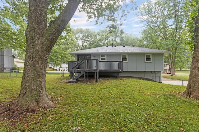 back of property with a yard, board and batten siding, stairs, and a deck