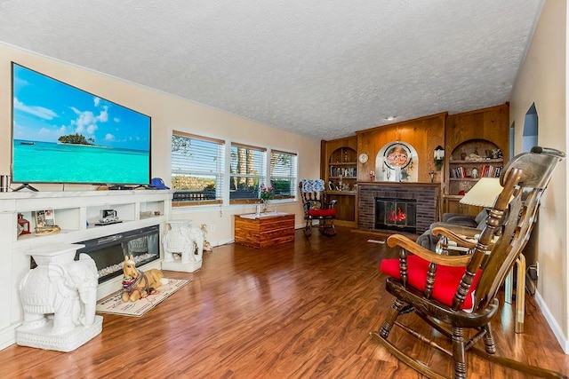 living room featuring hardwood / wood-style flooring, a textured ceiling, a brick fireplace, and built in shelves