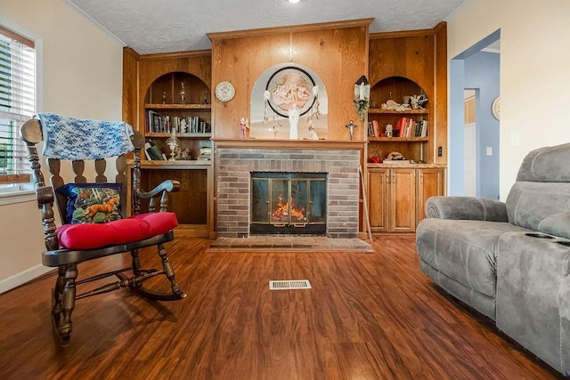 living room with wood-type flooring, a textured ceiling, and a brick fireplace