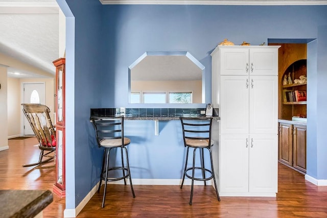 kitchen featuring a breakfast bar area, white cabinetry, hardwood / wood-style flooring, and kitchen peninsula