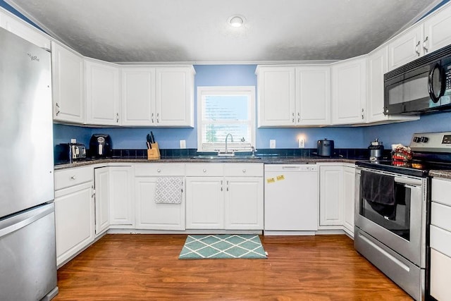 15124 NW County Road 14001st Rd, Drexel, MO 64742 - kitchen featuring a sink, dark countertops, white cabinetry, wood finished floors, and appliances with stainless steel finishes