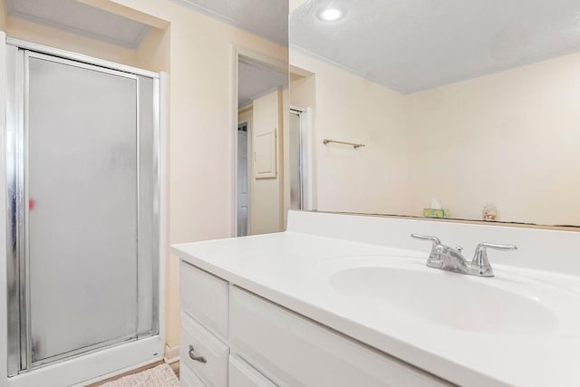 bathroom with a shower with shower door, ornamental molding, and vanity