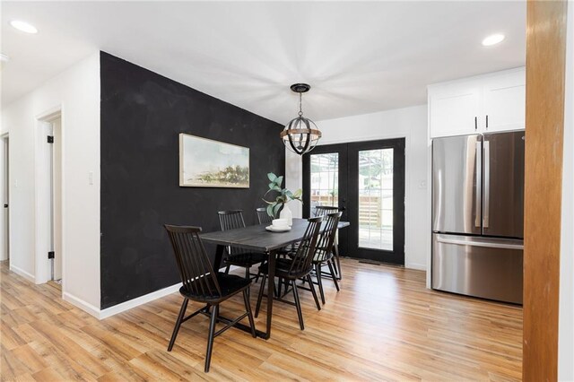 dining space with a notable chandelier, light hardwood / wood-style floors, and french doors