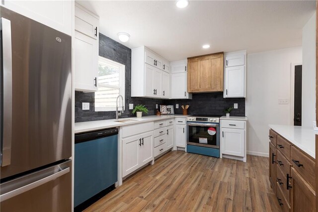 kitchen featuring backsplash, sink, appliances with stainless steel finishes, light hardwood / wood-style flooring, and white cabinetry