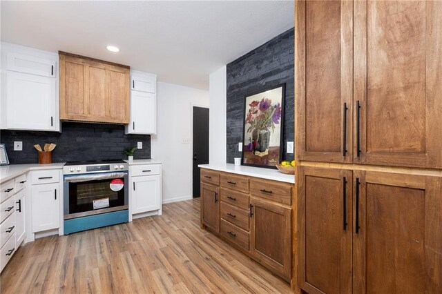 kitchen with white cabinets, tasteful backsplash, stainless steel electric range, and light hardwood / wood-style flooring