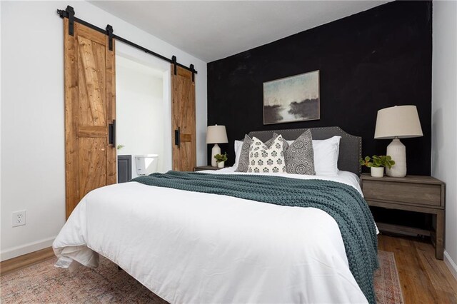 bedroom featuring hardwood / wood-style flooring and a barn door