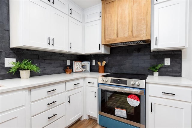 kitchen with stainless steel range with electric cooktop, light hardwood / wood-style flooring, decorative backsplash, exhaust hood, and white cabinets