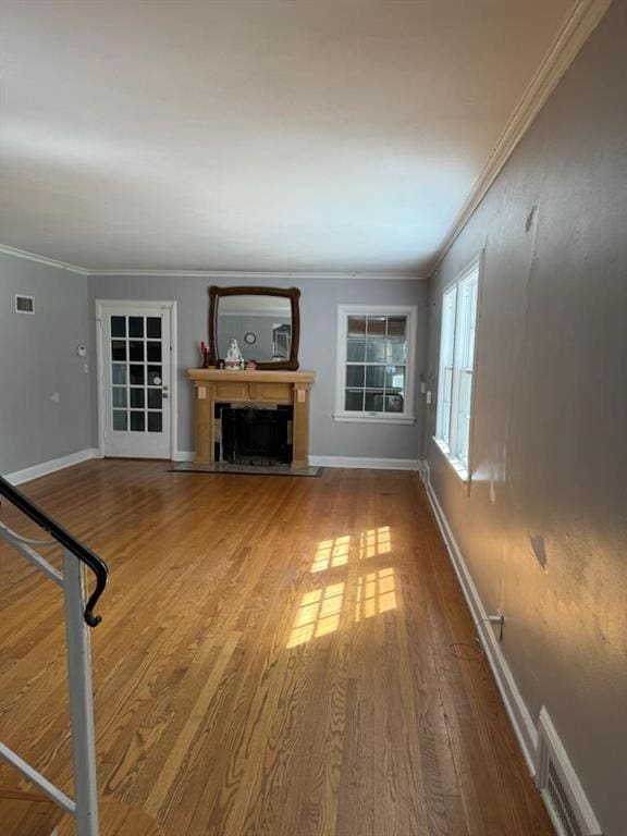 unfurnished living room with ornamental molding and hardwood / wood-style floors