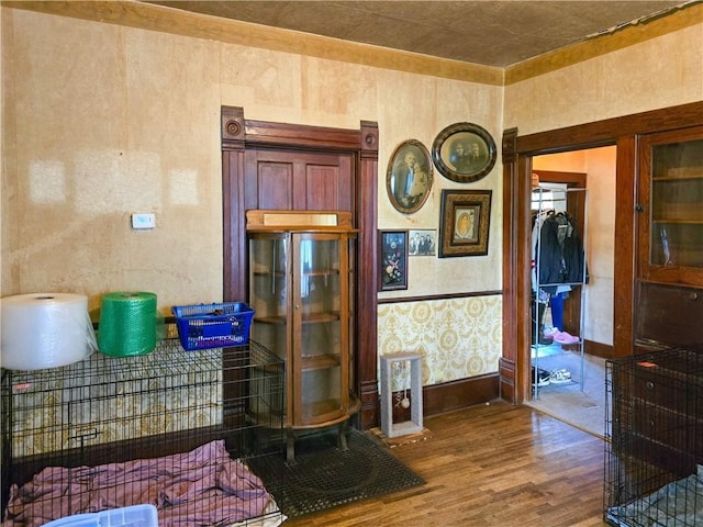 interior space featuring wallpapered walls, baseboards, and wood finished floors