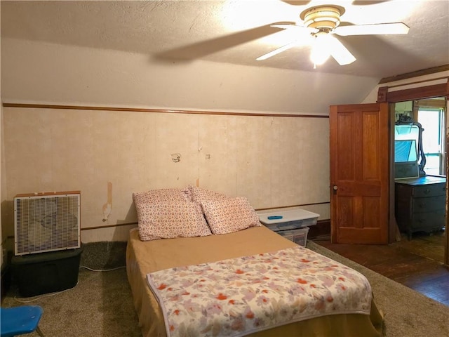 bedroom with a ceiling fan, dark wood-style flooring, vaulted ceiling, and a textured ceiling