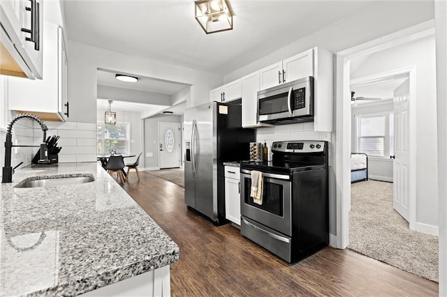 kitchen with plenty of natural light, backsplash, appliances with stainless steel finishes, and white cabinetry