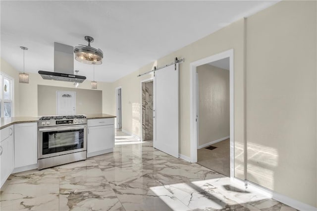 kitchen with a barn door, white cabinets, range hood, and stainless steel range with gas stovetop