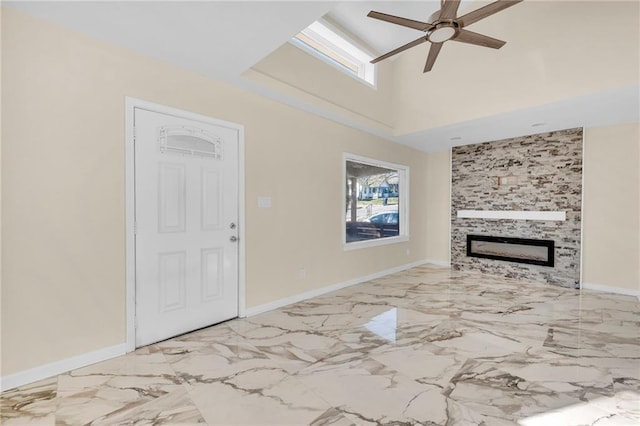 unfurnished living room with ceiling fan, a large fireplace, and a high ceiling