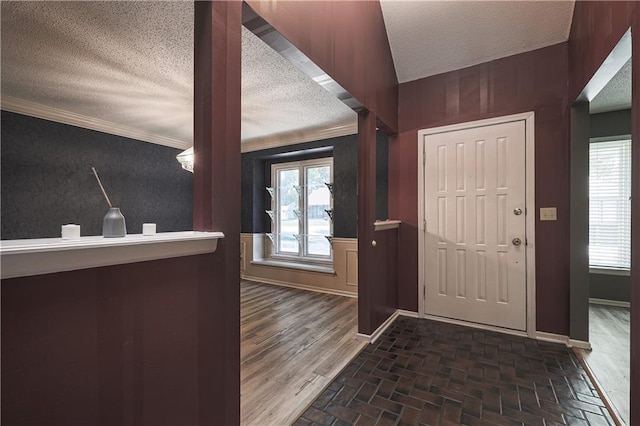 entryway featuring brick floor, a wealth of natural light, a textured ceiling, and baseboards