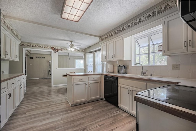 kitchen featuring black dishwasher, light wood finished floors, white cabinetry, a sink, and a peninsula