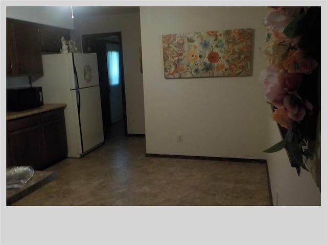 kitchen featuring white fridge and dark brown cabinets