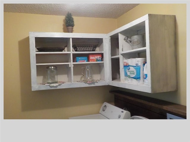 clothes washing area featuring washer / clothes dryer and a textured ceiling