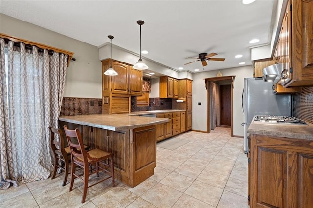 kitchen with pendant lighting, light tile patterned floors, a breakfast bar, backsplash, and kitchen peninsula