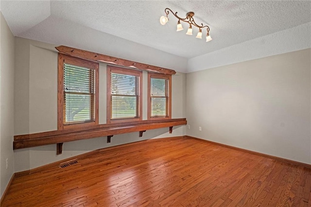 spare room with wood-type flooring and a textured ceiling