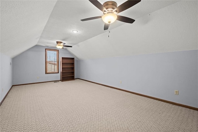 bonus room with lofted ceiling, ceiling fan, light carpet, and a textured ceiling