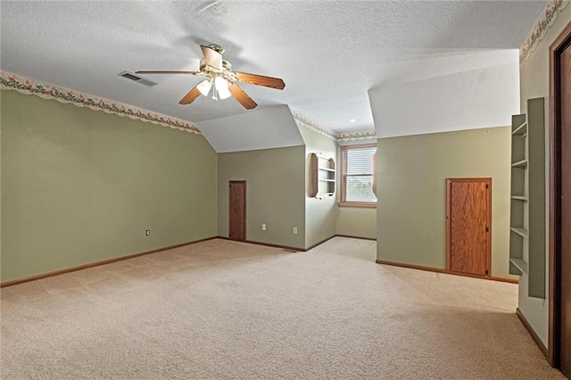 additional living space with vaulted ceiling, light colored carpet, ceiling fan, and a textured ceiling