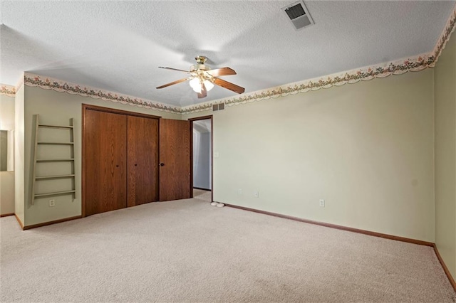 unfurnished bedroom with ceiling fan, light colored carpet, a closet, and a textured ceiling