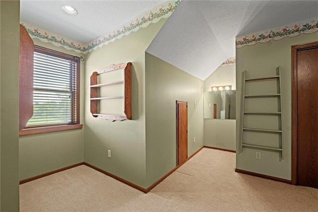 hall with vaulted ceiling, light carpet, and a textured ceiling